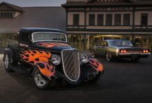 Black hot rod with red flames parked in front of building at night