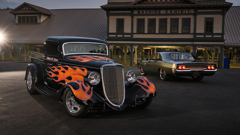 Black hot rod with red flames parked in front of building at night
