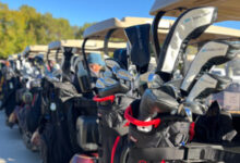 Golf glubs on back of row of golf carts