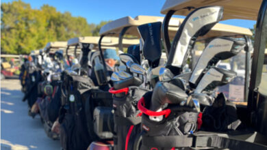 Golf glubs on back of row of golf carts