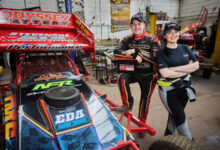 Lee and Jacklyn Fairhurst standing next to race car in garage