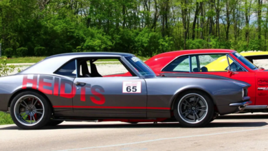 Lined of classic cars parked outside with Heidts logo on the side of first car