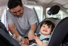 Man securing child in booster car seat