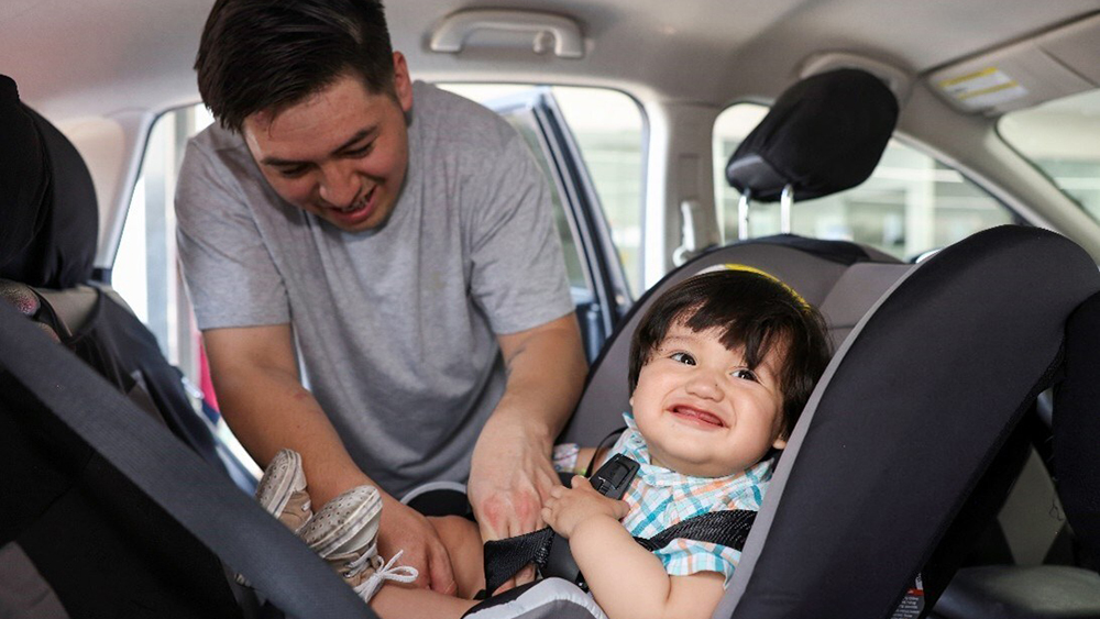 Man securing child in booster car seat