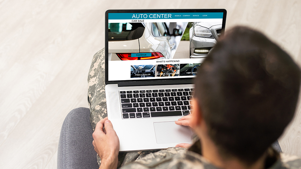 Person in chair buying car on laptop
