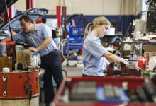 Students auto techs working on cars in garage