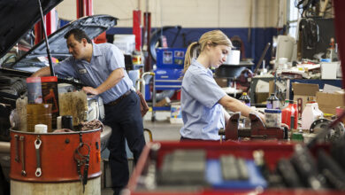 Students auto techs working on cars in garage