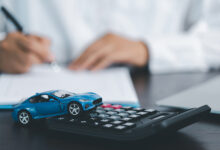 Blue Toy Car In Front Of Businessman Calculating Loan. Saving money for car concept, trade car for cash concept, finance concept.