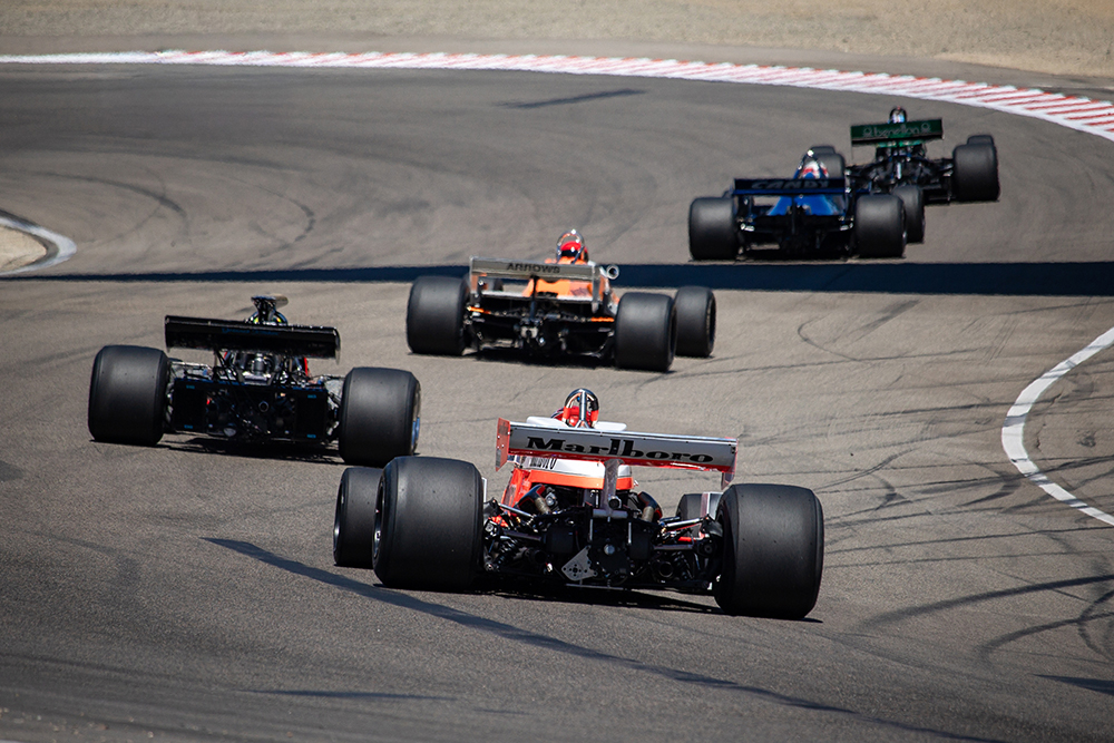 A line of formula one cars slowing down under safety car during the Mario Andretti Trophy Race