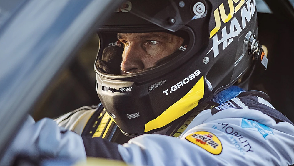 Closeup of Torsten Gross with Just Hand helmet sitting behind wheel of race car