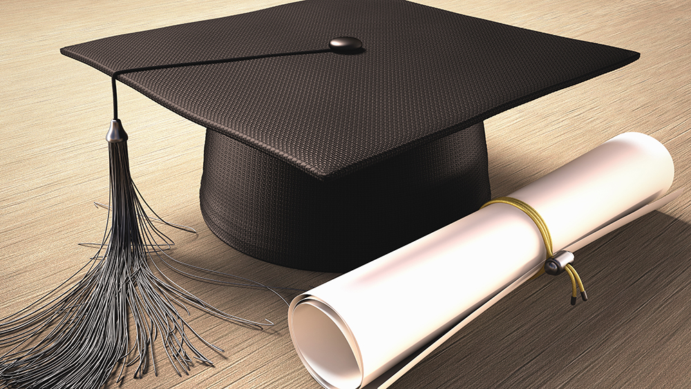 Graduation cap with diploma on table.