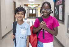 Two young students with backpacks in school hallway