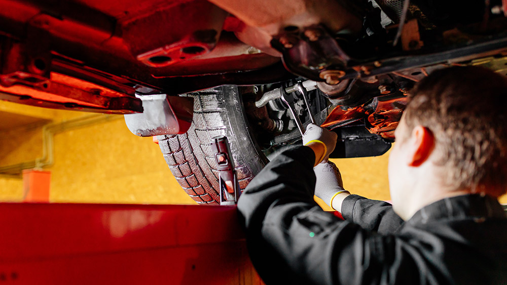 Car mechanic installing wheel alignment sensors, car suspension adjustment. Car mechanic at work