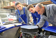 Instructor with trainees working on car engine