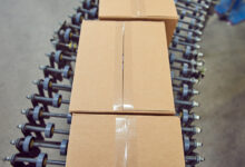 Parcels for delivery on an industrial roller conveyor belt in a fully automated online retailer warehouse.