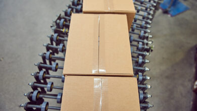 Parcels for delivery on an industrial roller conveyor belt in a fully automated online retailer warehouse.