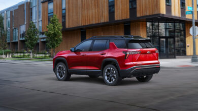 Red 2025 Chevrolet Equinox RS driving in front of building