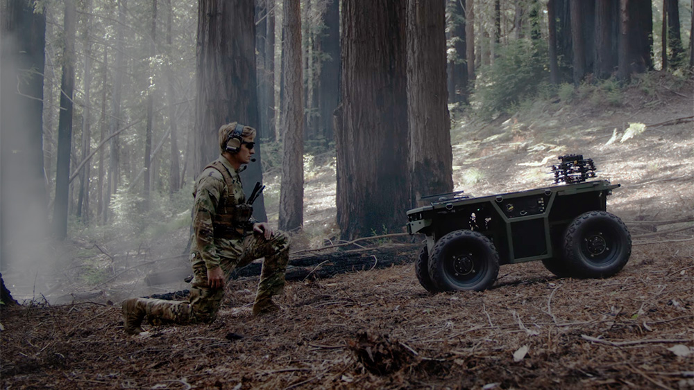 Soldier and NOMAD, an unmanned ground vehicle controlled by Scout's Fury autonomy system, in forest copy