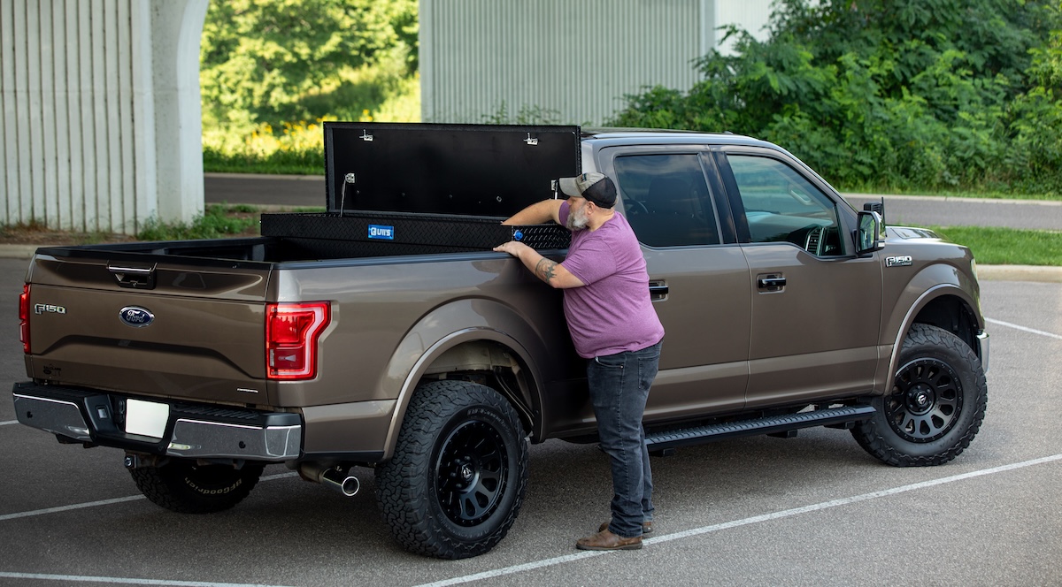 toolbox cargo man reaches into truck bed-mounted toolbox from lippert