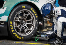 Closeup of driver working on Goodyear Eagle tire on race car
