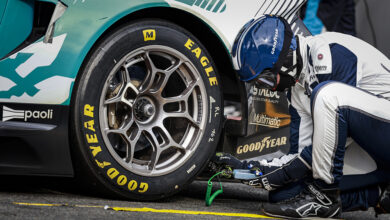 Closeup of driver working on Goodyear Eagle tire on race car