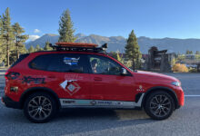 Red BMW X5 driving on road with mountains in the background