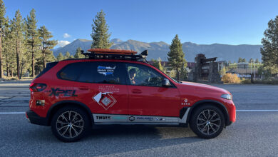 Red BMW X5 driving on road with mountains in the background