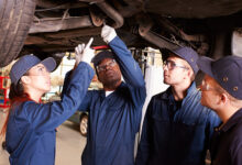 Teacher Helping Students Training To Be Car Mechanics
