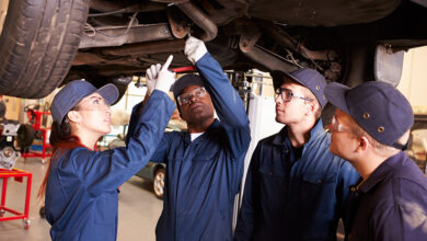 Teacher Helping Students Training To Be Car Mechanics