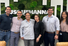 Susquehanna Growth Equity and Tint World reps in front of Susquehanna logo on wall