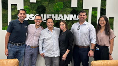 Susquehanna Growth Equity and Tint World reps in front of Susquehanna logo on wall