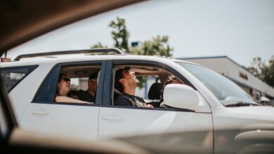 gen z drivers laugh in a silver sedan in traffic