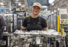 Tech looking at camera in Toyota hyprid production plant