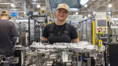 Tech looking at camera in Toyota hyprid production plant