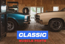 Two classic muscle cars facing each other in garage