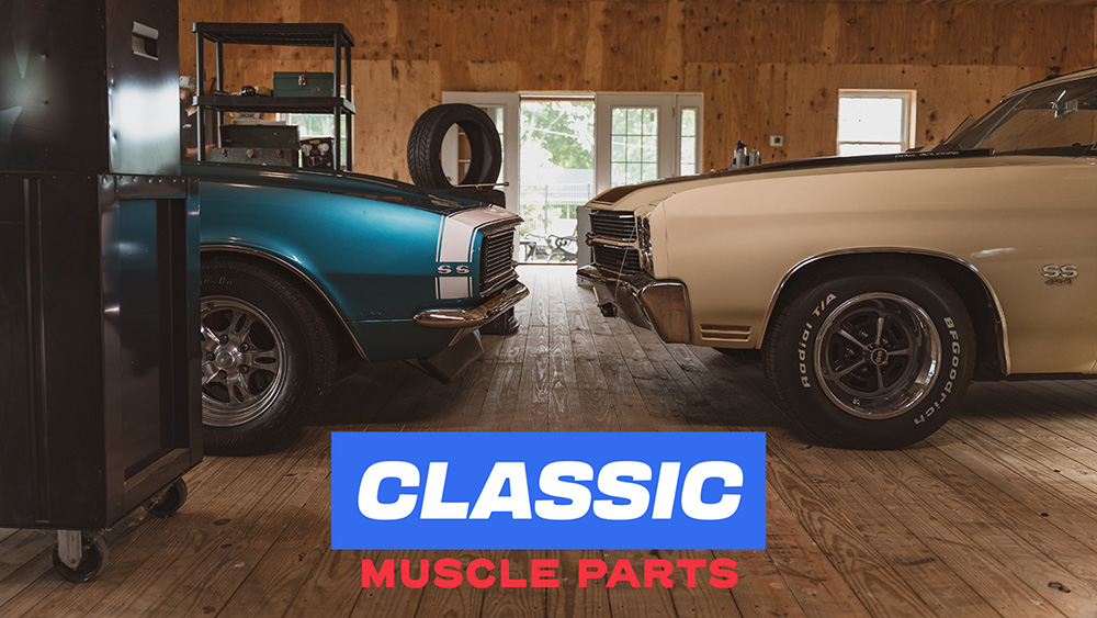 Two classic muscle cars facing each other in garage