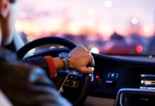 in-car time behind shot of driver with hands on wheel in traffic