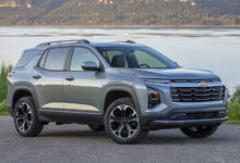 Front 3/4 view of a 2025 Chevrolet Equinox LT in Sterling Gray Metallic parked near a large body of water.