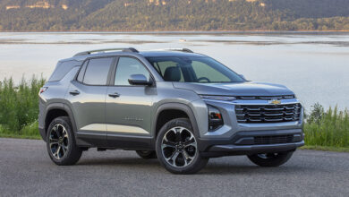 Front 3/4 view of a 2025 Chevrolet Equinox LT in Sterling Gray Metallic parked near a large body of water.