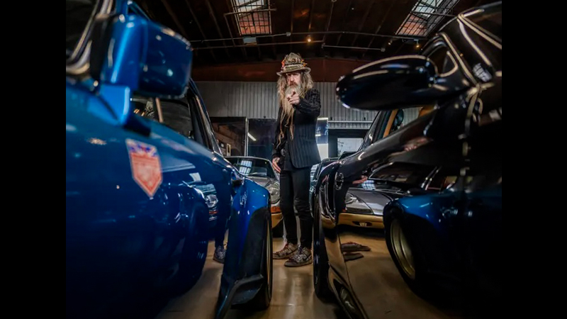 Magnus Walker pointing surrounded by Porsches