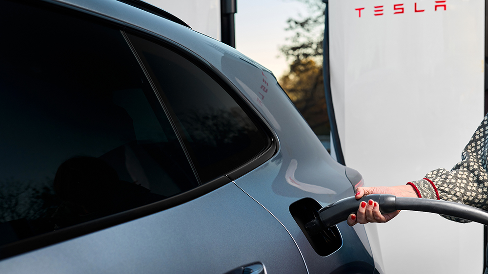 Person plugging Porsche 2026 Taycan into Tesla Supercharger