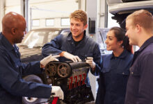 Teacher Helping Students Training To Be Car Mechanics