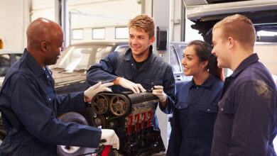 Teacher Helping Students Training To Be Car Mechanics