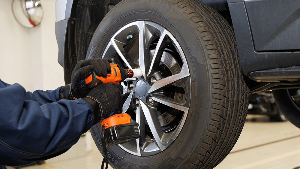 Car mechanic worker doing tire or wheel replacement with pneumat