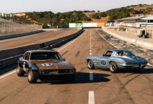 Two classic race cars parked on track