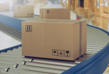 Cardboard boxes on conveyor rollers ready to be shipped by courier for distribution.