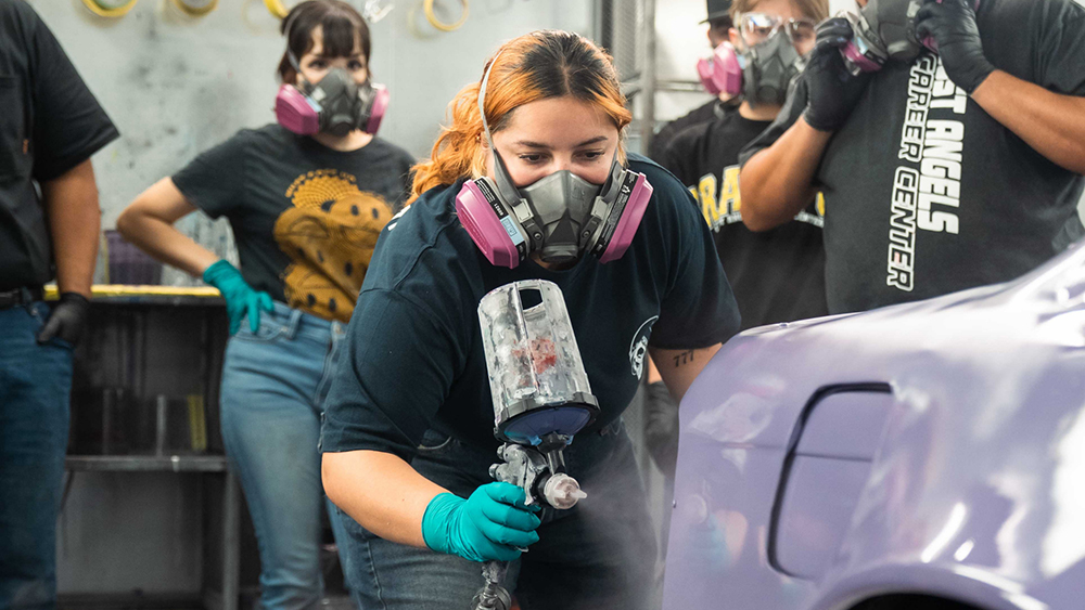 Woman wearing mask and spray painting car