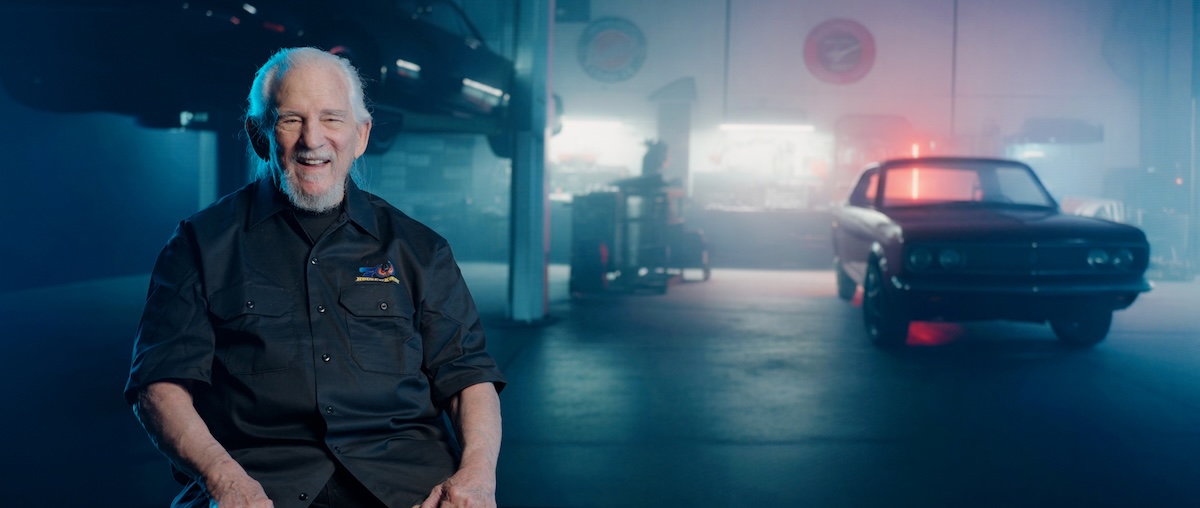 house of kolor's jon kosmoski smile in garage in front of classic vehicle