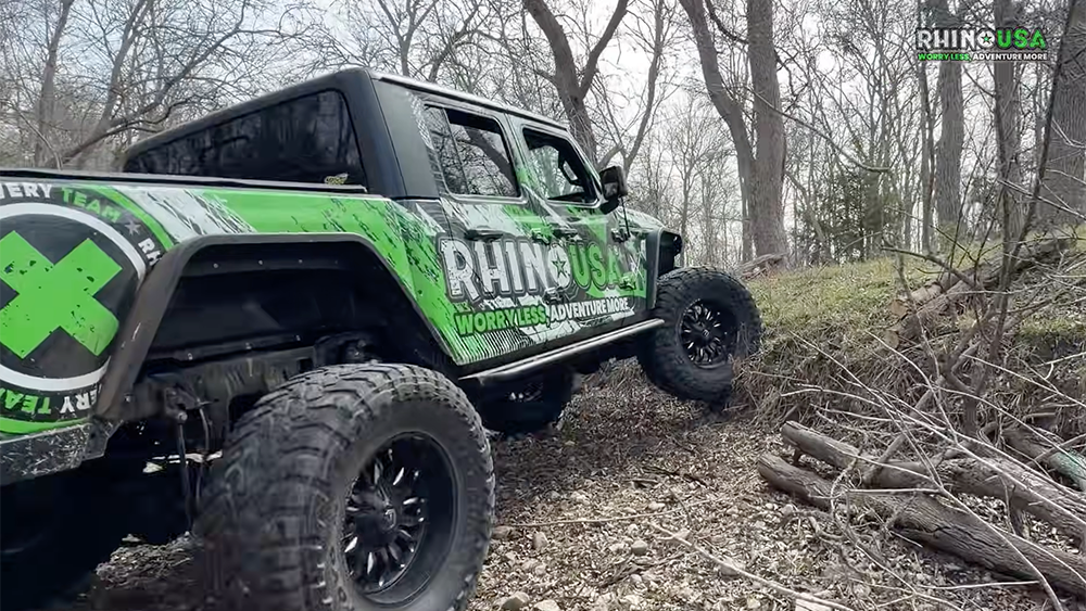 Rhino USA branded truck driving up hill in woods