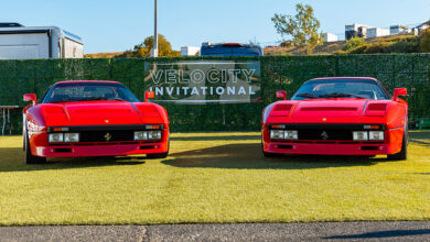 Two red Ferraris parked in front of Velocity International sign